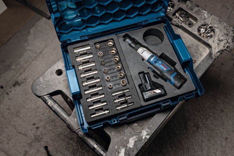 Cordless ratchet wrench kit with sockets and battery organized in a blue carrying case.