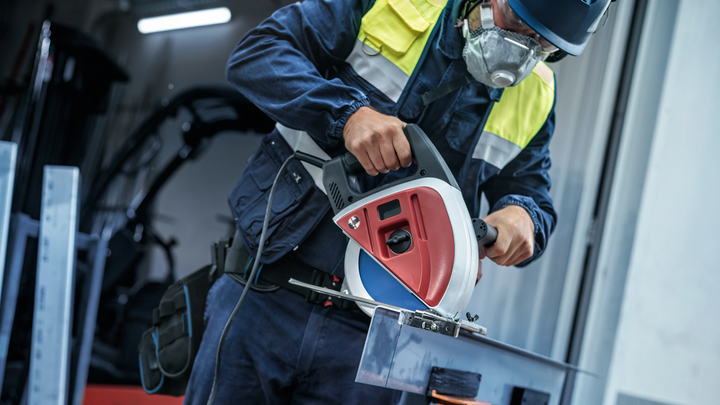 Object #200585157: 7557703_app_web_04 A person wearing safety equipment cuts a metal beam with a circular saw.