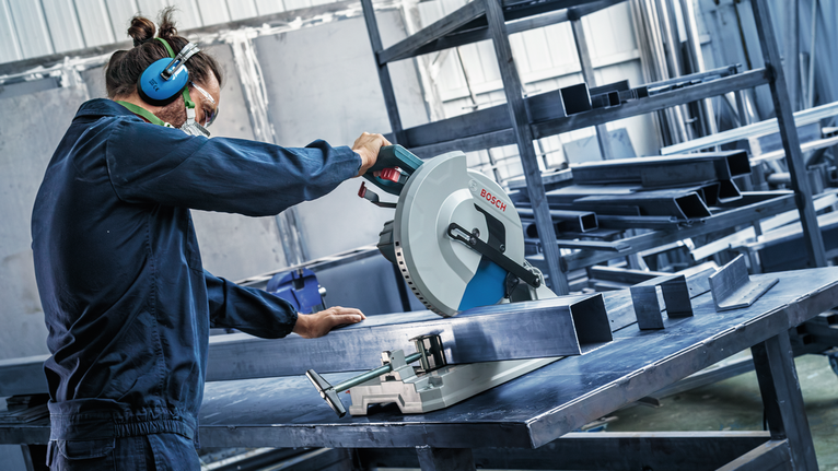 EXPERT Steel Circular Saw Blade, 254 x 2.6/2.2 x 25.4 mm, T60 Person wearing safety equipment uses a circular saw to cut a metal beam on a worktable.