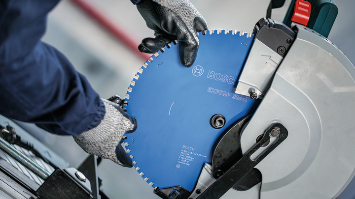Object #200585210: 7557706_app_web_04 Person wearing safety equipment installs a circular saw blade onto a cut-off machine.