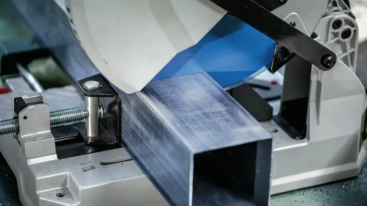 Object #200585211: 7557706_app_web_05 Metal cutting saw slices through a large steel beam in an industrial setting.