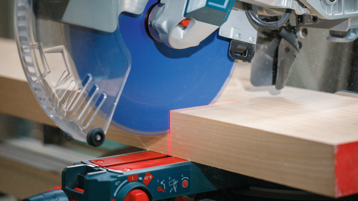 Object #200585313: 7557711_app_web_01 Circular saw cutting a thick wooden board in a workshop.