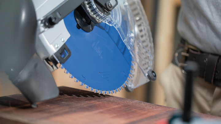Object #200585318: 7557711_app_web_04 Circular saw cutting through a wooden board, person wearing safety equipment.