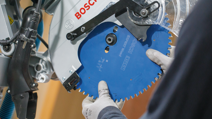 Object #200585319: 7557711_app_web_05 Person wearing safety equipment installs a circular saw blade into a power saw.