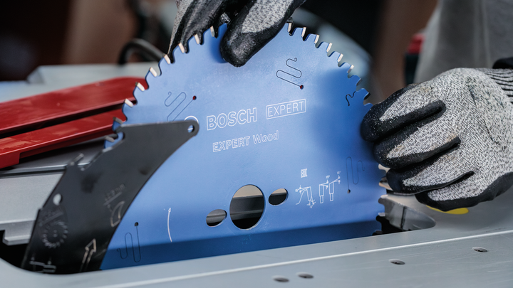 Object #200585339: 7557712_app_web_04 Person wearing safety equipment installs a circular saw blade into a table saw.