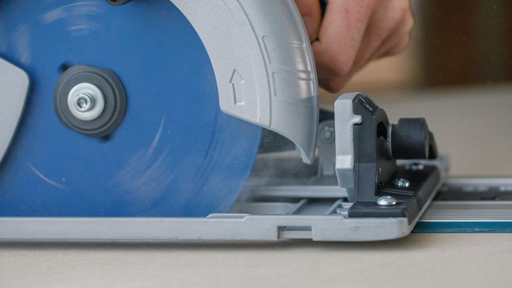 Object #200585524: 7557691_app_web_01 Person operating a circular saw to cut wood along a guide rail.