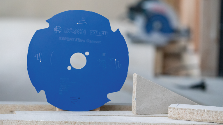 EXPERT Fibre Cement Circular Saw Blade, 165 x 2.2/1.6 x 20 mm, T4 Blue circular saw blade standing upright beside fiber cement boards.