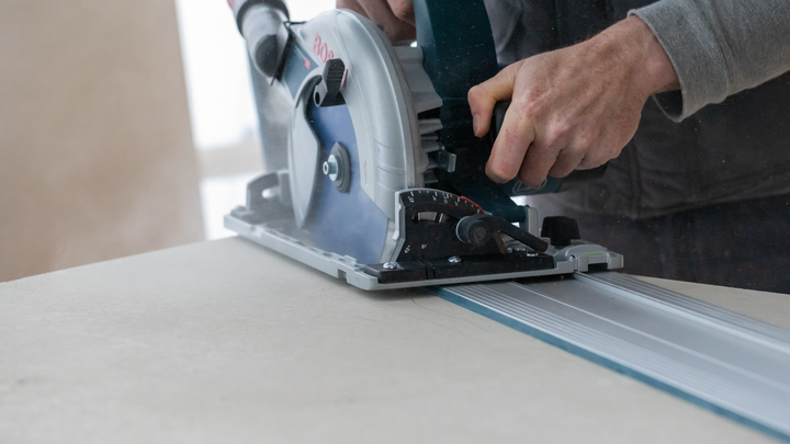 Object #200585530: 7557691_app_web_07 Person guides a circular saw along a track to cut a large board.