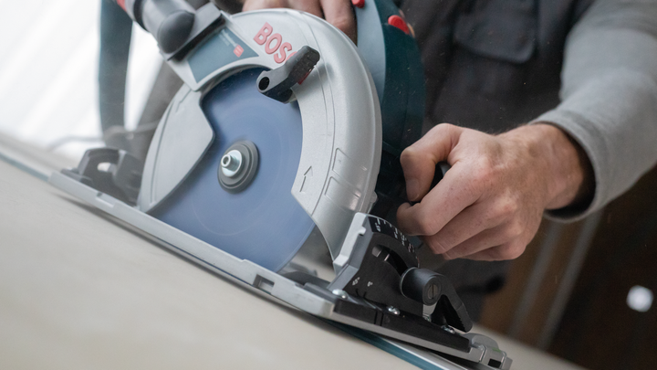 Object #200585531: 7557691_app_web_08 Person operating a circular saw to cut through a wooden board.