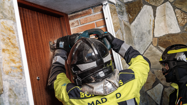 Object #200585885: 7785204_app_web_10 Person wearing safety equipment operates a power tool to cut open a wooden door.