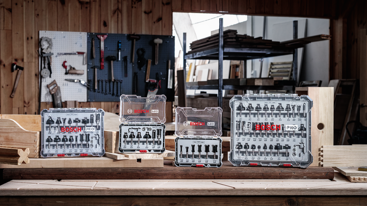 Router bit sets displayed on a wooden workbench in a carpenter’s workshop.