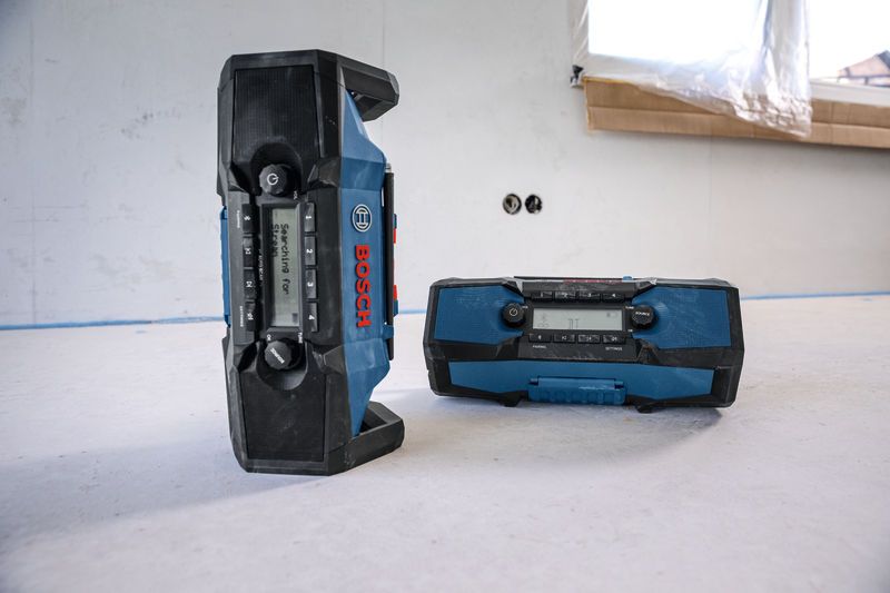 Two rugged blue jobsite radios placed on a construction floor.