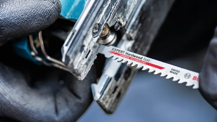 Object #200597811: 2793294_app_web_02 Person wearing safety equipment inserts a jigsaw blade into a power tool.