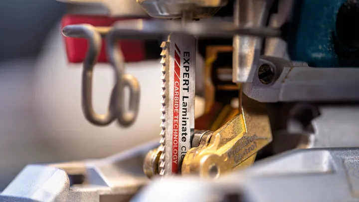Close-up of a jigsaw blade with carbide teeth mounted in a power tool.