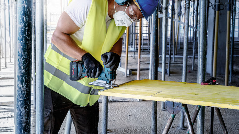 EXPERT ‘Multi Material‘ T 367 XHM Jigsaw Blade 3-pc Person wearing safety equipment uses a jigsaw to cut wood on a construction site.