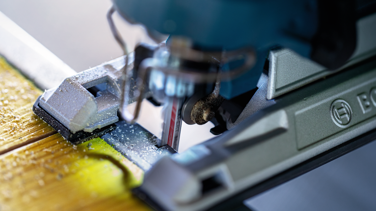 EXPERT ‘Multi Material‘ T 367 XHM Jigsaw Blade 3-pc Jigsaw cutting through a wooden board, producing fine sawdust.