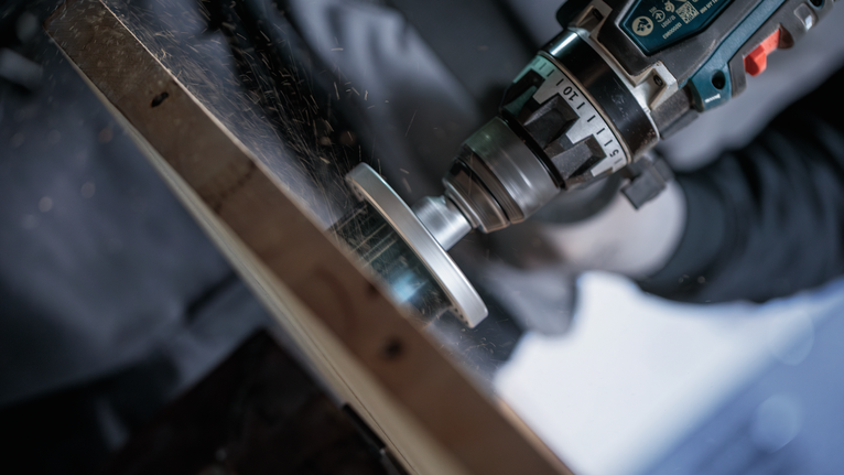 A person wearing safety equipment grinds metal, creating sparks.