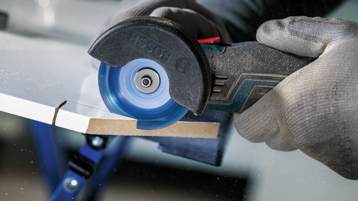 Object #200609211: 2840086_app_web_01 Person wearing safety equipment uses a circular saw to cut a sheet material.