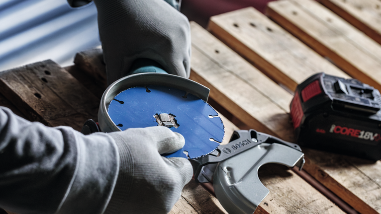 EXPERT Multi Material Carbide Cutting Disc, 125 x 22.23 mm, X-Lock Person wearing safety equipment attaches a circular saw blade to a power tool.