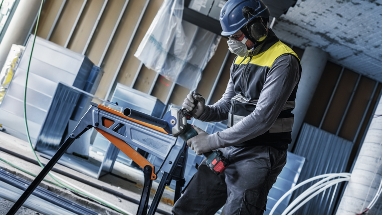 EXPERT Multi Material Carbide Cutting Disc, 125 x 22.23 mm, X-Lock Person wearing safety equipment drills into metal tubing on a workbench.