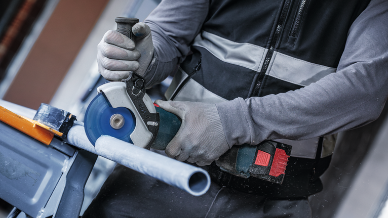 EXPERT Multi Material Carbide Cutting Disc, 125 x 22.23 mm, X-Lock Person wearing safety equipment cuts a plastic pipe with a circular saw.