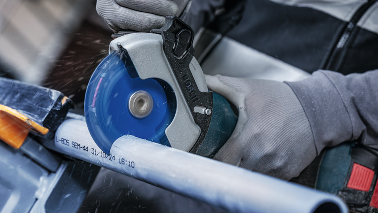 EXPERT Multi Material Carbide Cutting Disc, 125 x 22.23 mm, X-Lock Person wearing safety equipment cuts a plastic pipe with a circular saw.