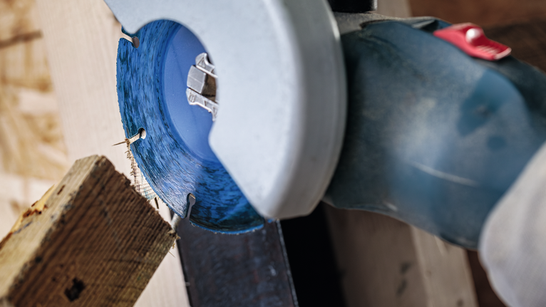 EXPERT Multi Material Carbide Cutting Disc, 125 x 22.23 mm, X-Lock Circular saw blade cuts through a wooden board in a workshop.