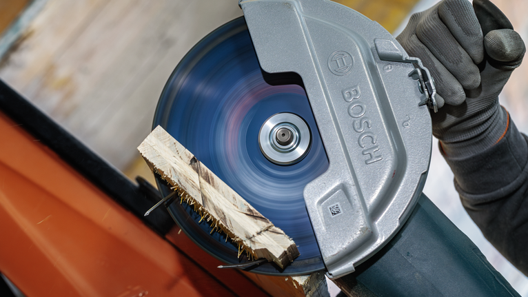 Person wearing safety equipment cuts wood with a circular saw.