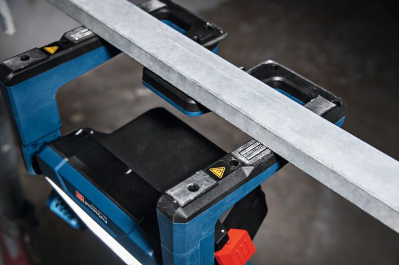 Cordless jobsite light illuminates a workspace underneath a metal beam.