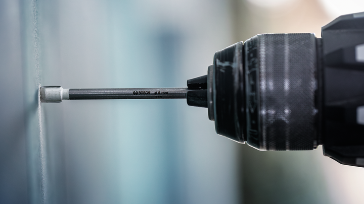 Drill driving a screw into a wall.