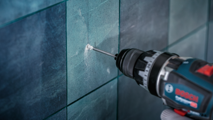 Power drill making a precise hole in a tiled wall.