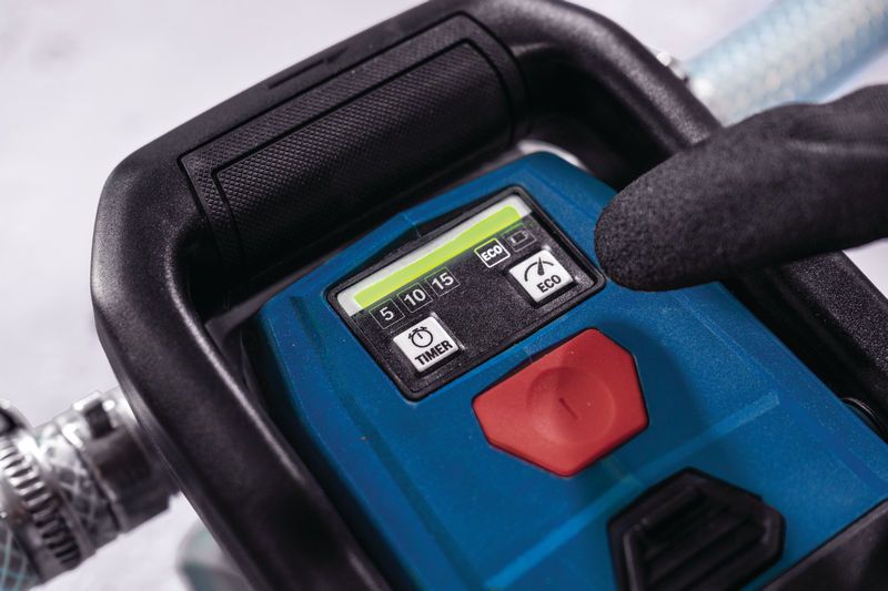 A person wearing safety equipment presses a timer button on a portable power tool.