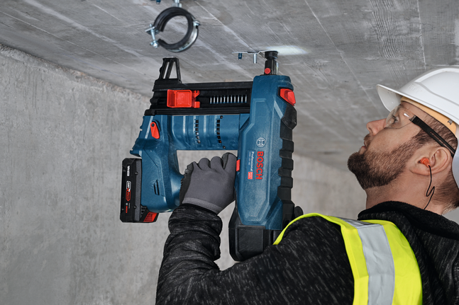 A person wearing safety equipment uses a power tool to install a metal hanger with external thread M8.