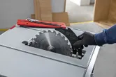 Person wearing safety equipment changing a blade on a table saw.