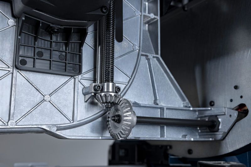 Close-up of a metal gear mechanism inside a table saw base.