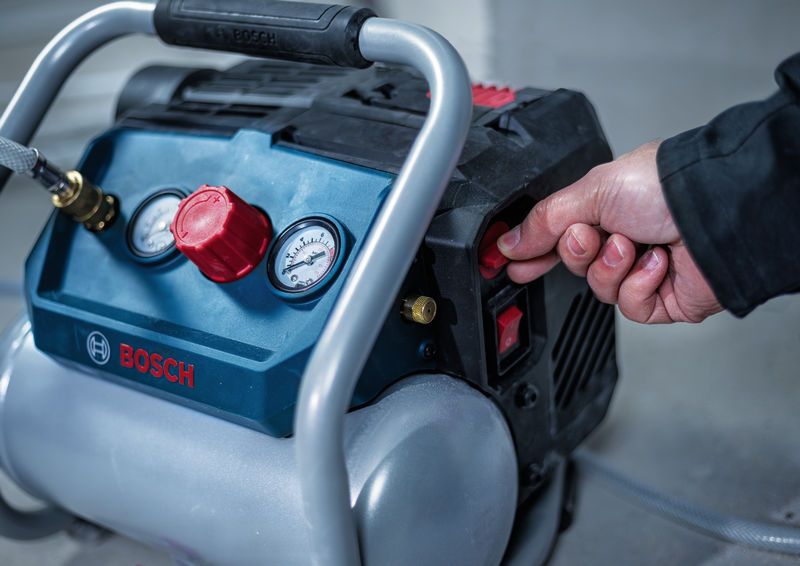 Person turns on a portable air compressor in an indoor workspace.