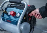Person turns on a portable air compressor in an indoor workspace.