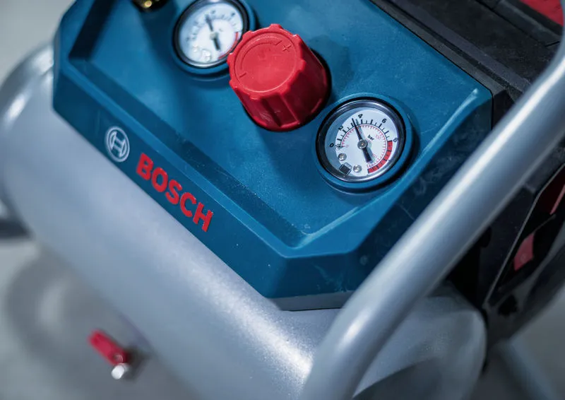 Close-up of a control panel featuring two pressure gauges and a large red knob.