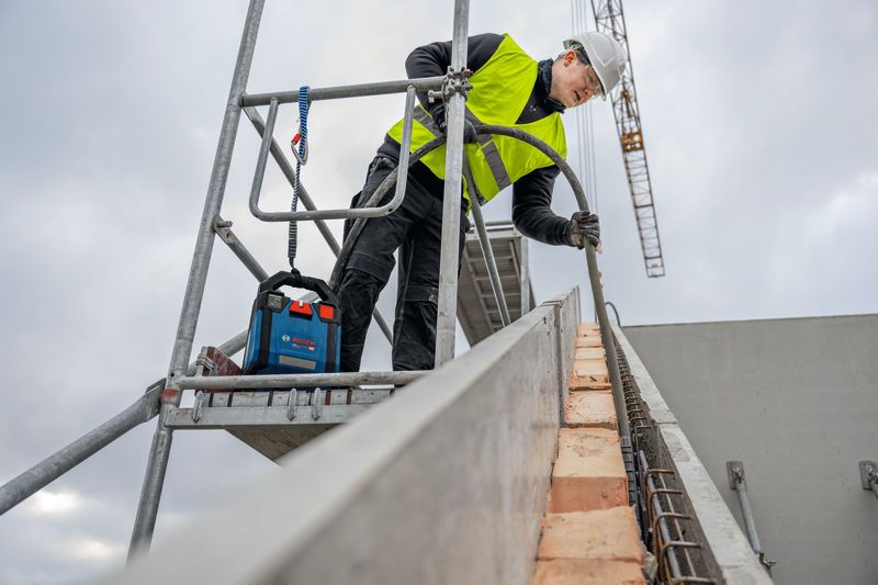 Person wearing safety equipment working on scaffolding at a construction site.