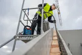 Person wearing safety equipment working on scaffolding at a construction site.