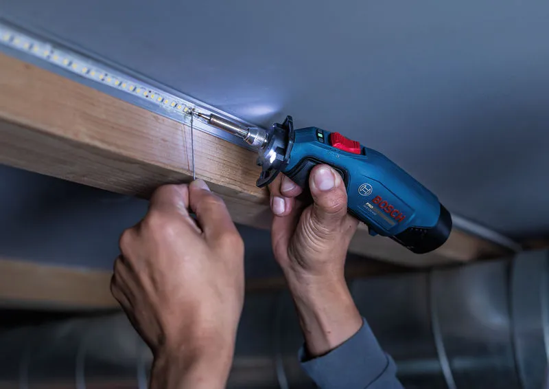 A person solders wire connections to LED lights with a cordless soldering iron.