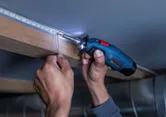 A person solders wire connections to LED lights with a cordless soldering iron.