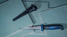 Hand saw and blade cover placed on stacked drywall sheets.