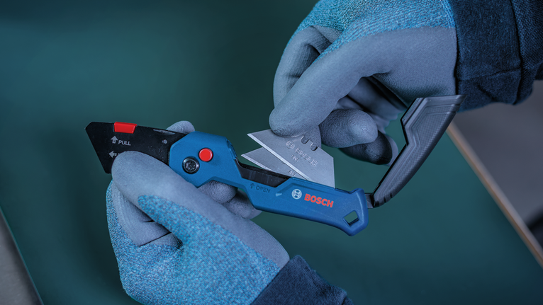 Person wearing safety equipment replaces the blade on a utility knife.