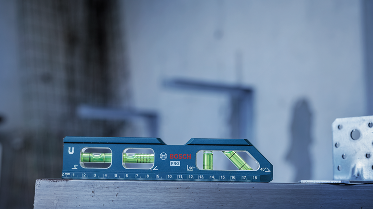 Blue spirit level tool rests on a metal surface at a construction site.