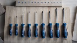 Set of blue and black screwdrivers arranged by size on a wooden surface.