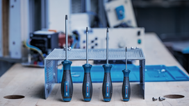 Four screwdrivers of varying sizes stand upright on a metal workbench in a workshop.