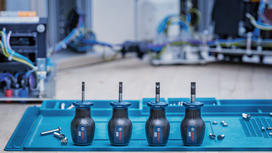 Four screwdrivers stand on a blue tray next to scattered screws in an electrical workspace.