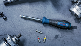 Screwdriver with interchangeable bits on a metal work surface.