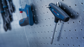 T-handle hex key and other tools hanging on a perforated metal board.
